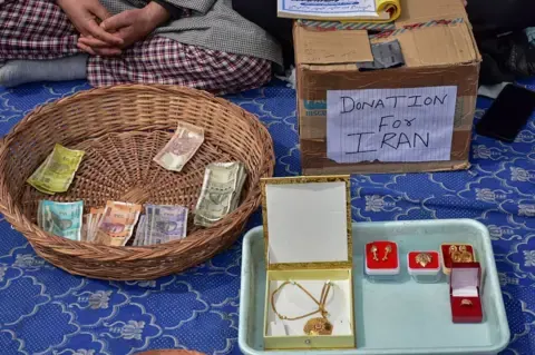 LightRocket via Getty Images Indian Rupee banknotes, gold items, is seen collected by the volunteers of Shiite Muslim community during a do…